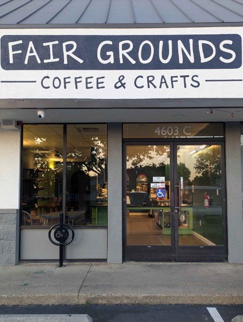 Photo displaying the Fair Grounds storefront. Depicts a beige building with the Fair Grounds logo painted at the top.